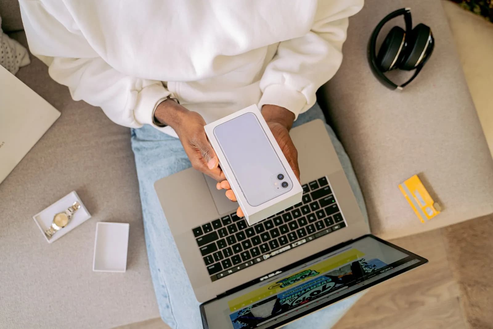 Woman using smartphone for online shopping with credit card in hand, festive background lighting.