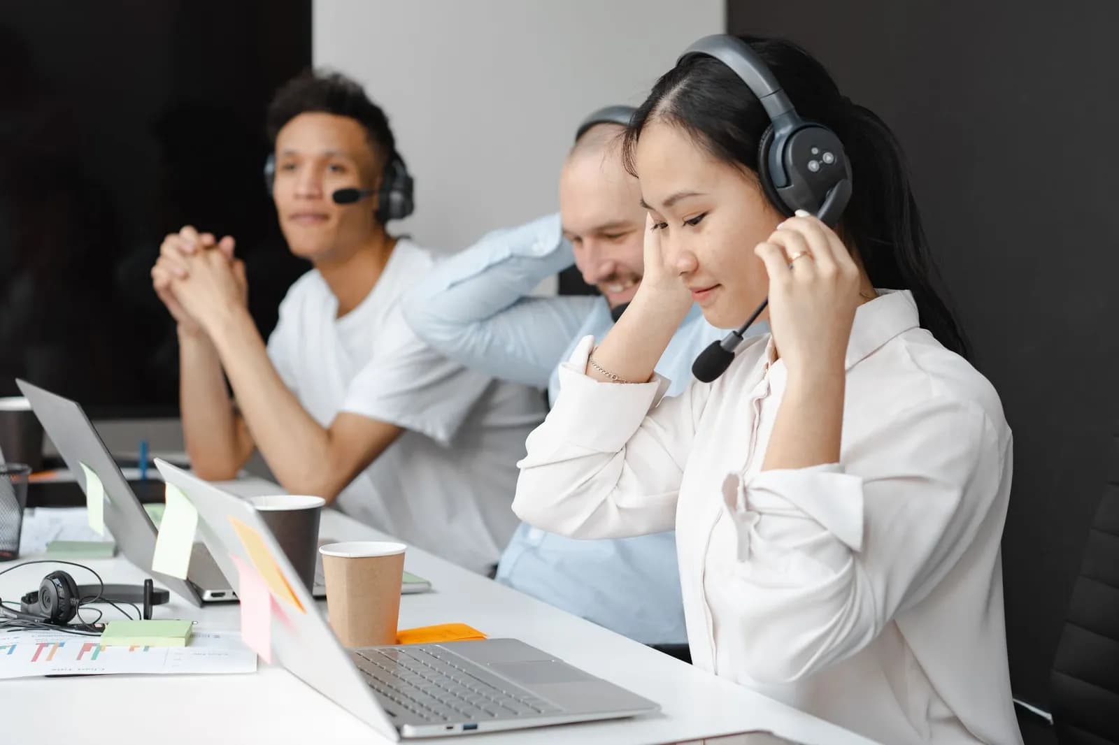 Employee in a suit working at a call center, focused on his laptop with a headset.
