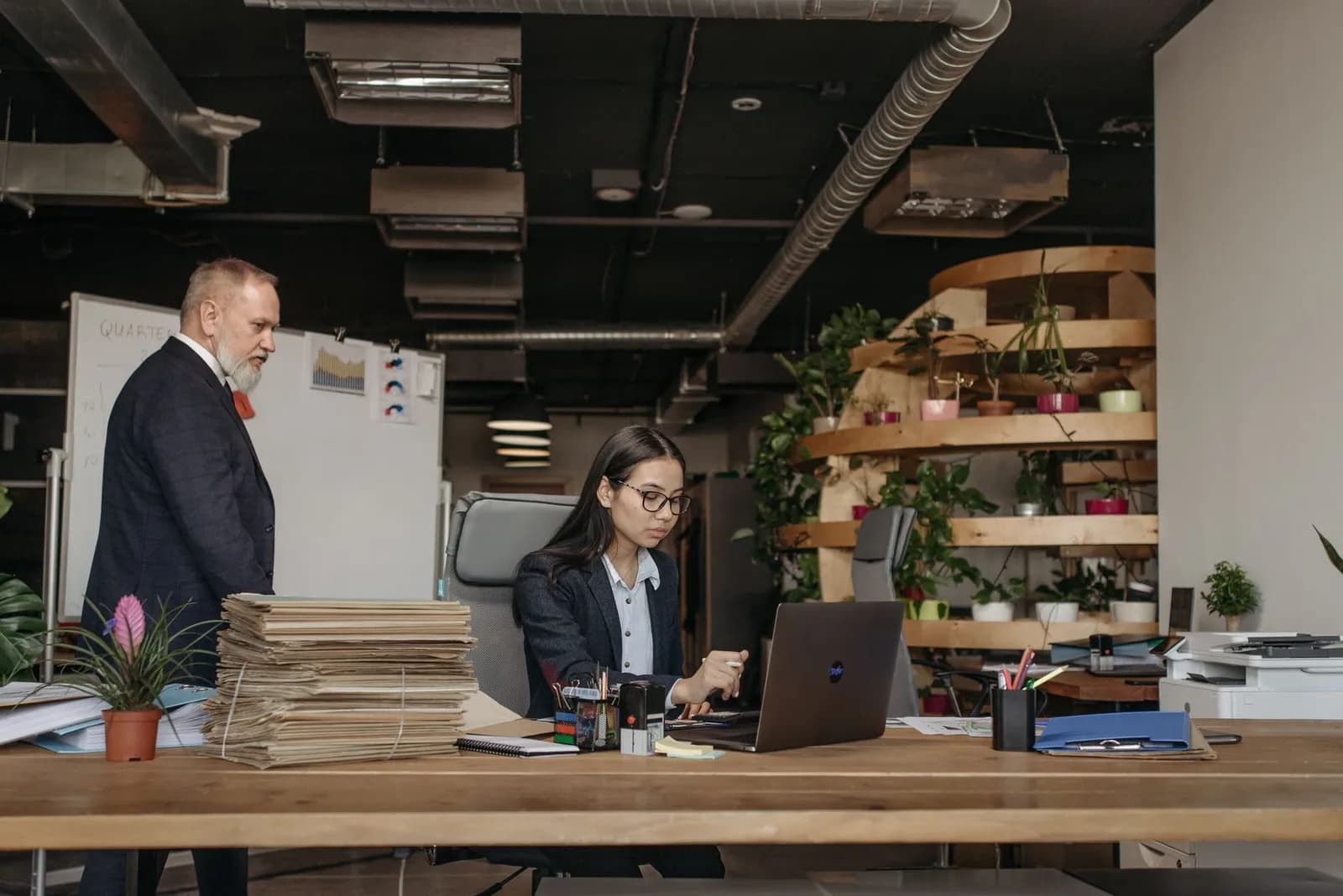 Business team in an office working together with modern equipment, plants, and documents.