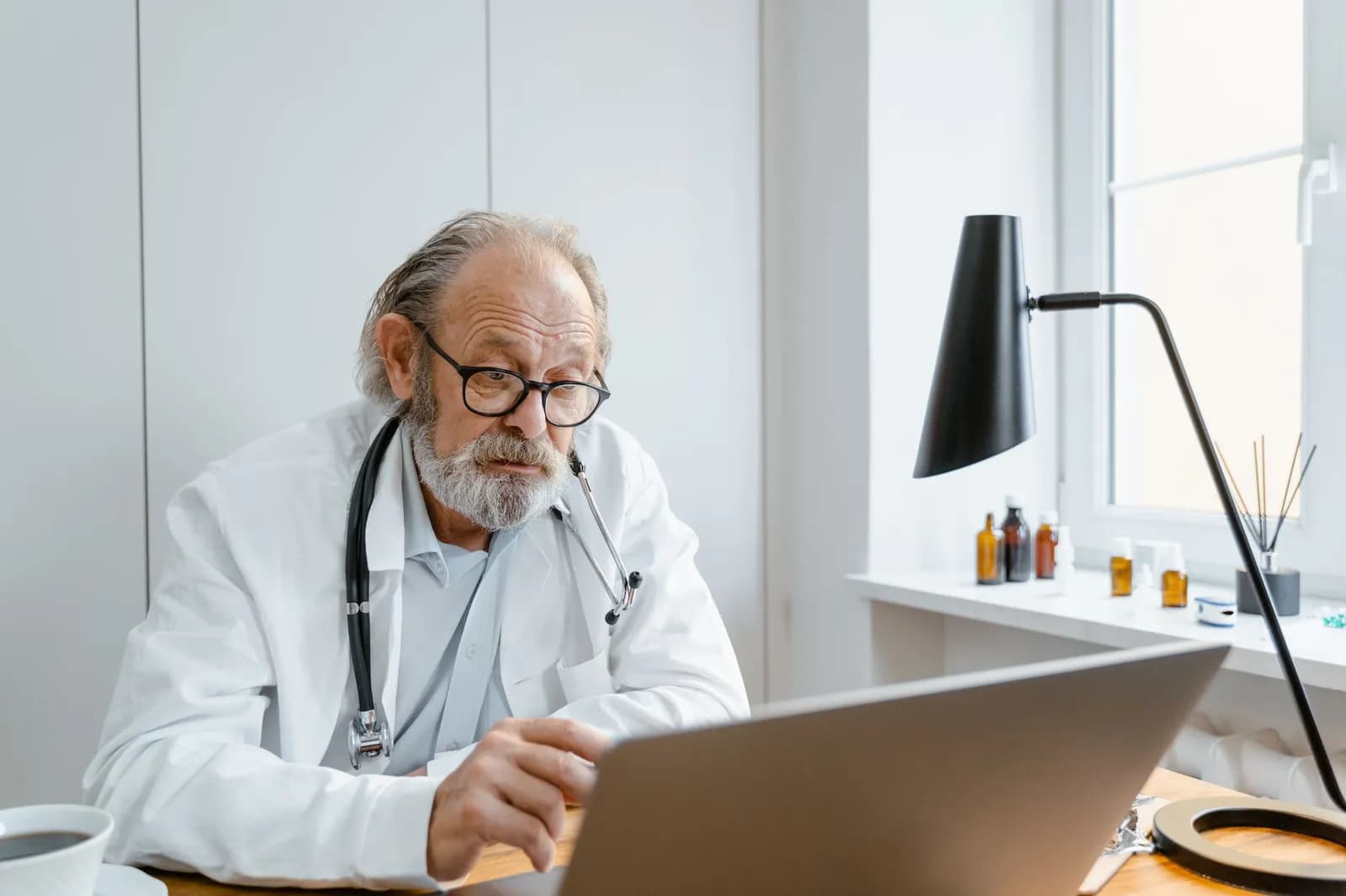 Eye care professional in clinic using ophthalmology equipment, wearing glasses and a lab coat.