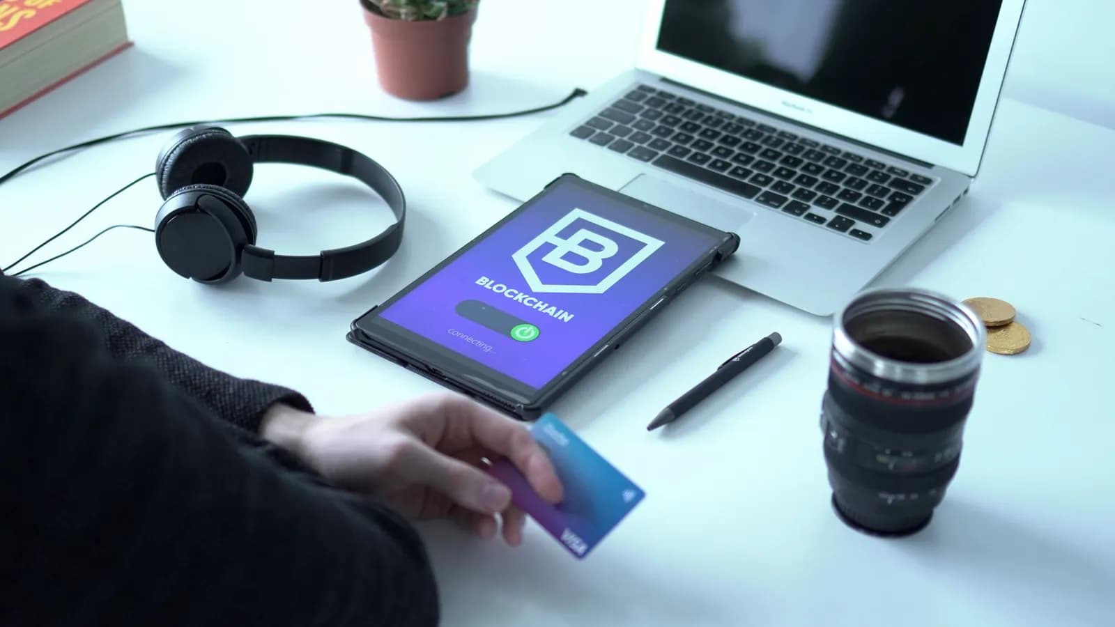 Modern workspace featuring blockchain technology. Laptop, tablet, and card on a desk.