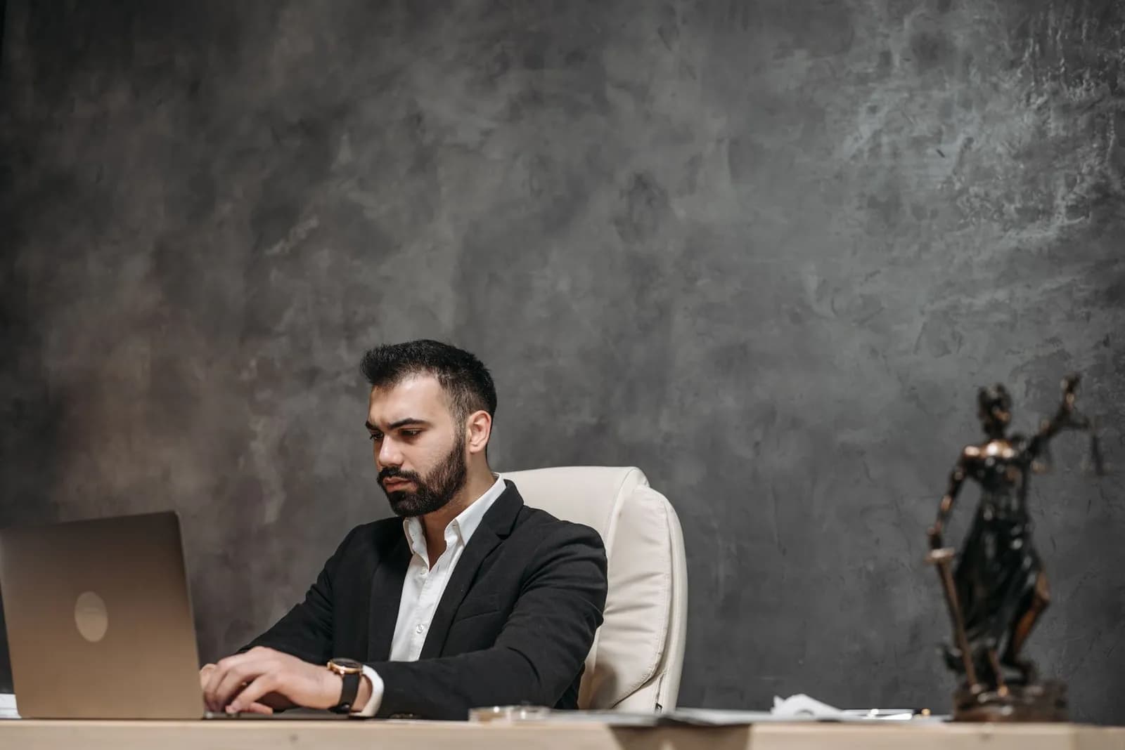 Crop concentrated Asian male judge in formal clothes sitting using modern netbook while working in law office