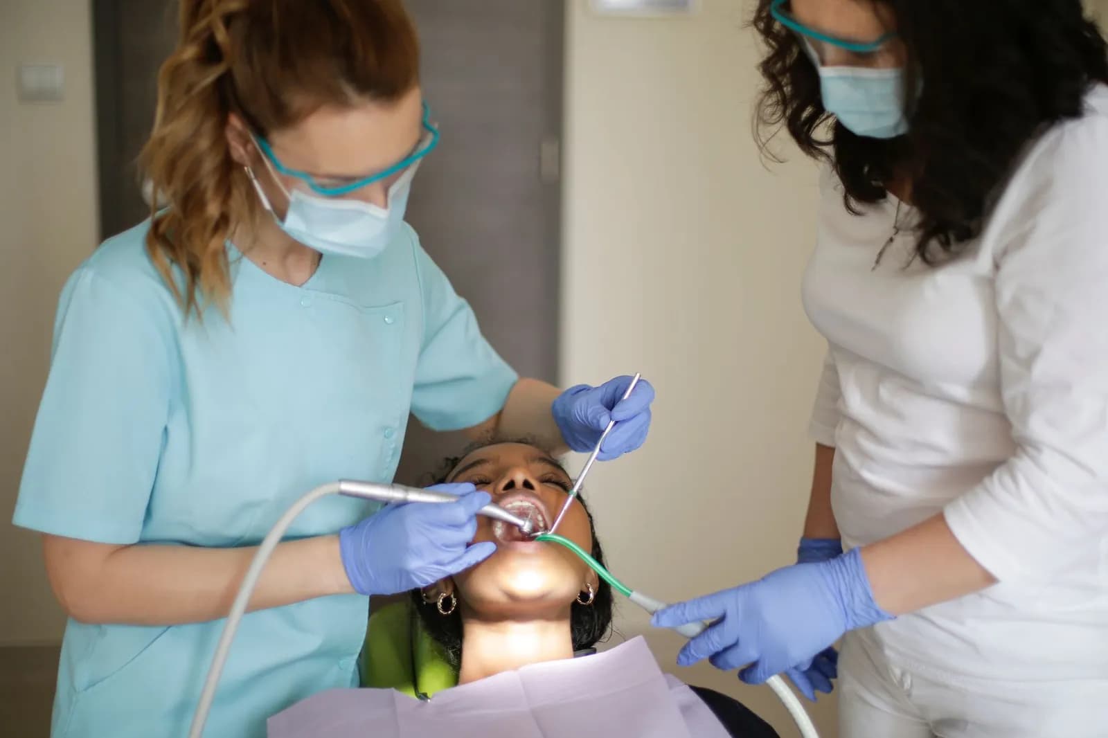 Faceless crop dentist in latex gloves holding box with burs for dental drill while working in modern clinic