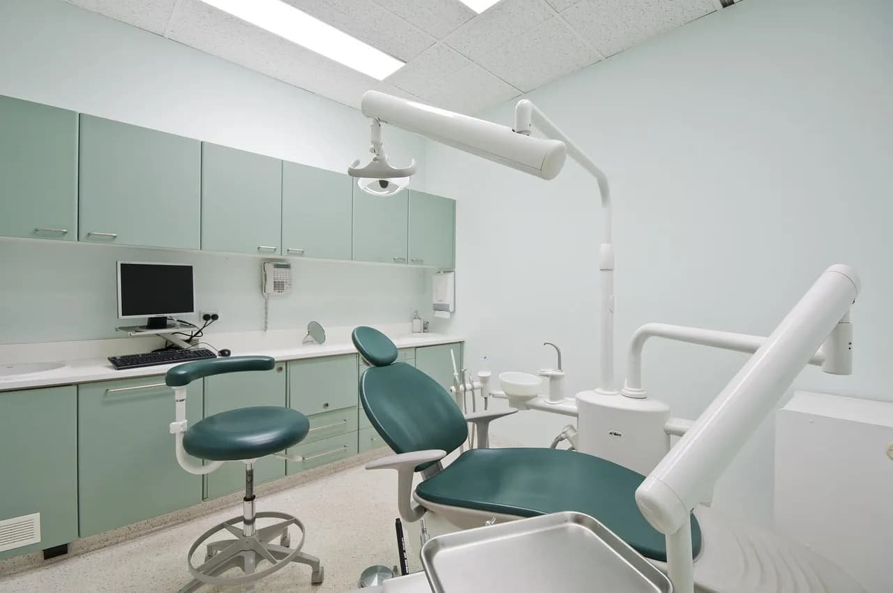 A dentist shows proper brushing technique using a dental model to a patient in a clinic.
