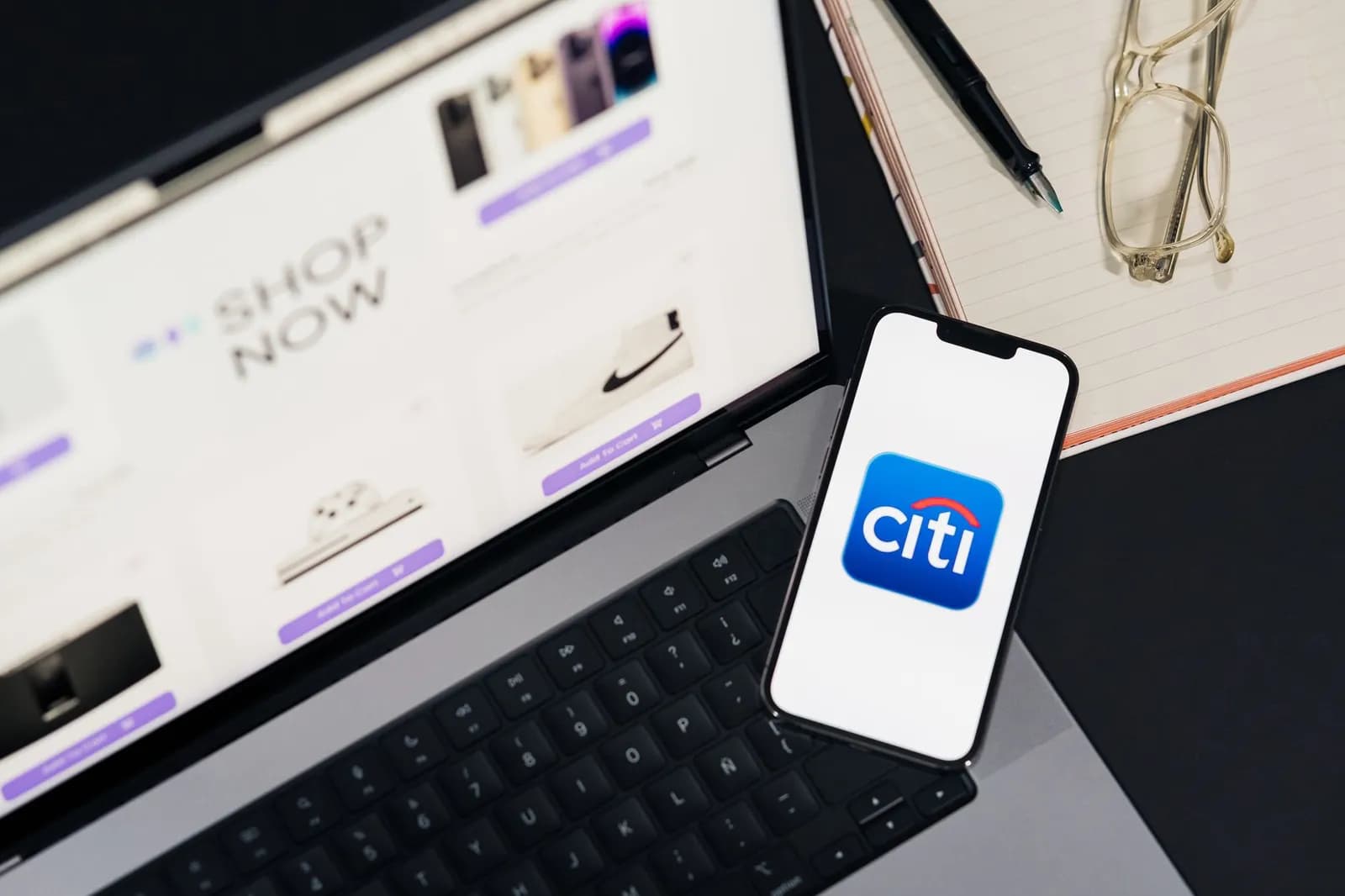 Laptop and smartphone showcasing online shopping and mobile payment setup on desk.