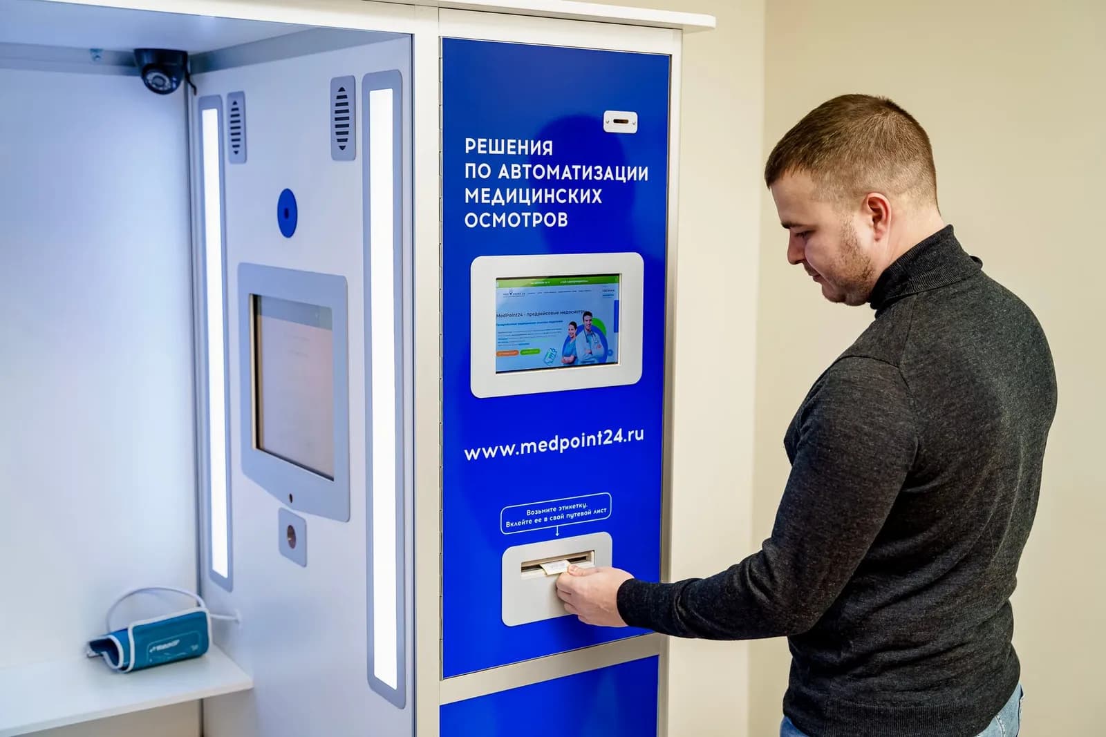 A person interacts with an automated medical kiosk featuring health technology solutions.