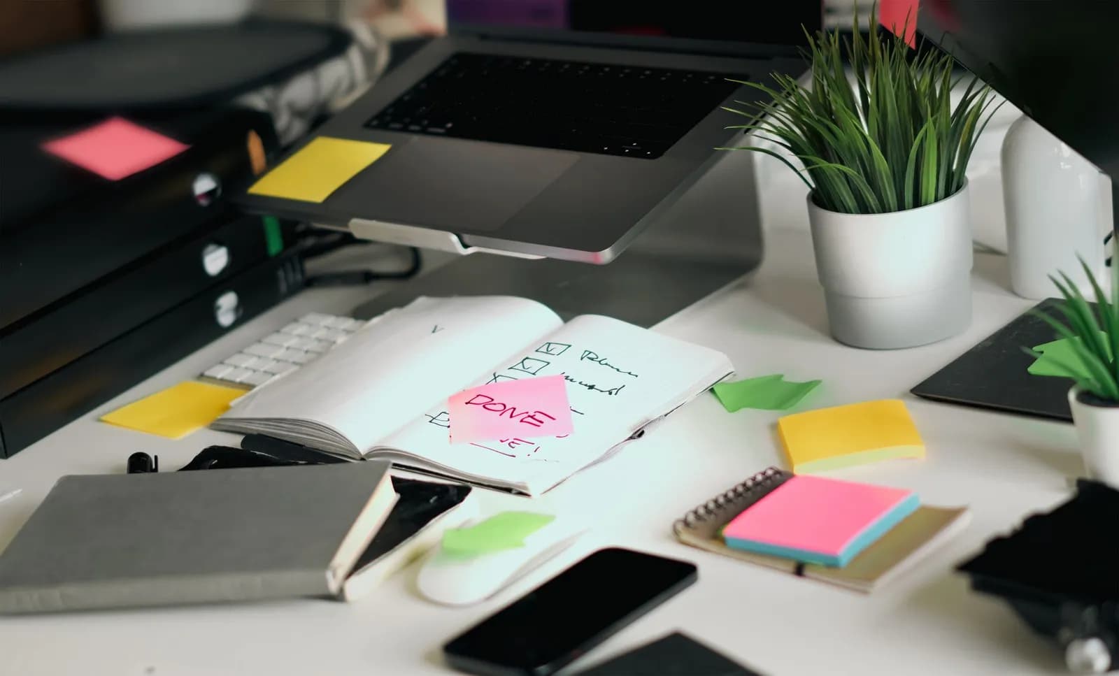 A laptop with green sticky notes and a pen on a wooden desk, symbolizing startup planning.