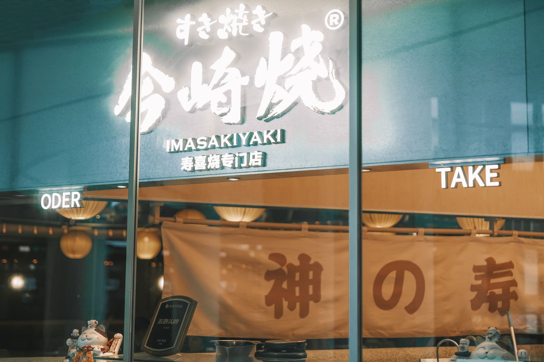 Illuminated Japanese restaurant facade featuring neon signs and decor.