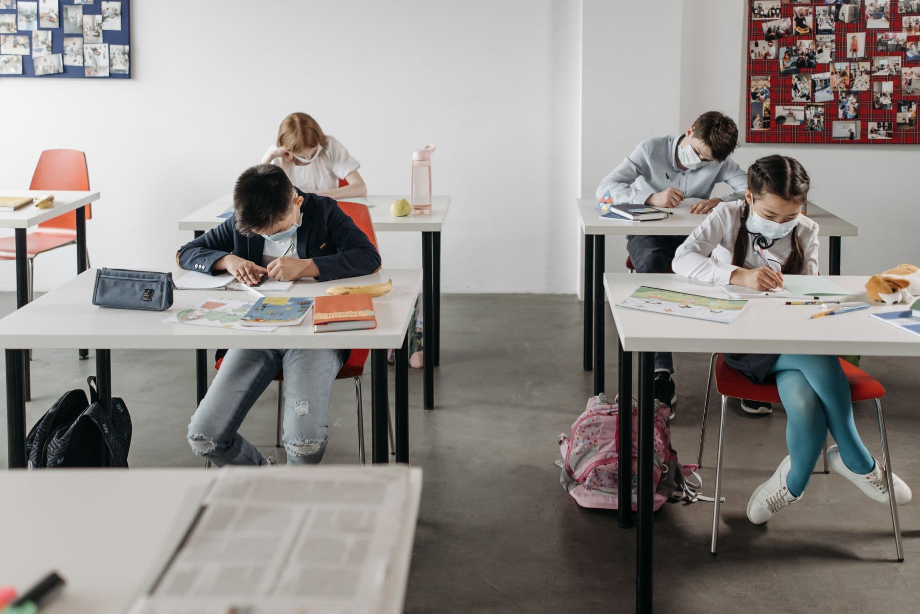 Students wearing masks studying diligently in a classroom with social distancing measures.