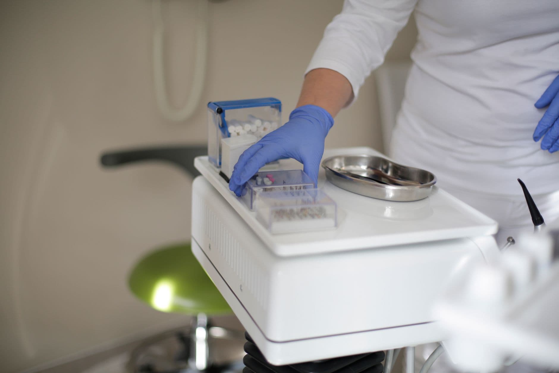 Faceless crop dentist in latex gloves holding box with burs for dental drill while working in modern clinic