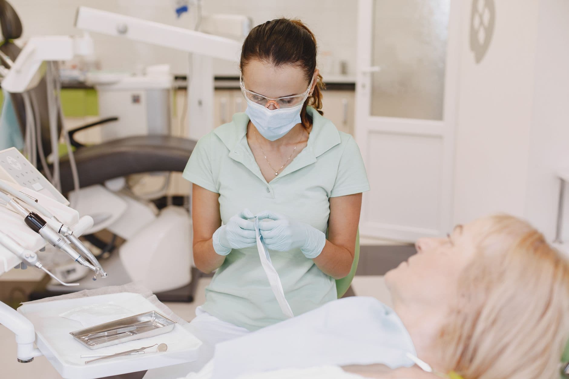Dentist in mask preparing dental tools for patient in a modern office.