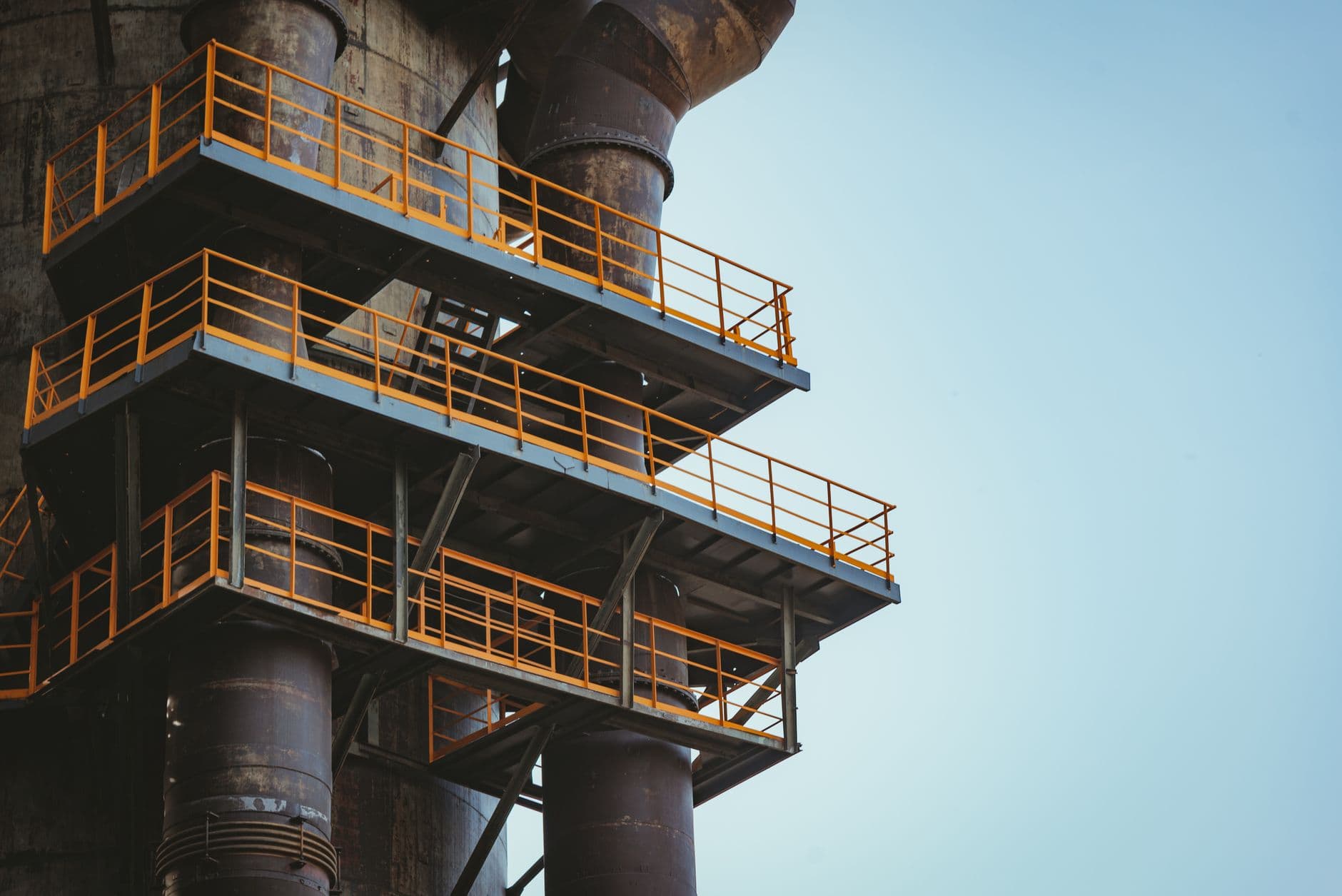 Close-up view of industrial metal balconies and pipes against a clear sky.