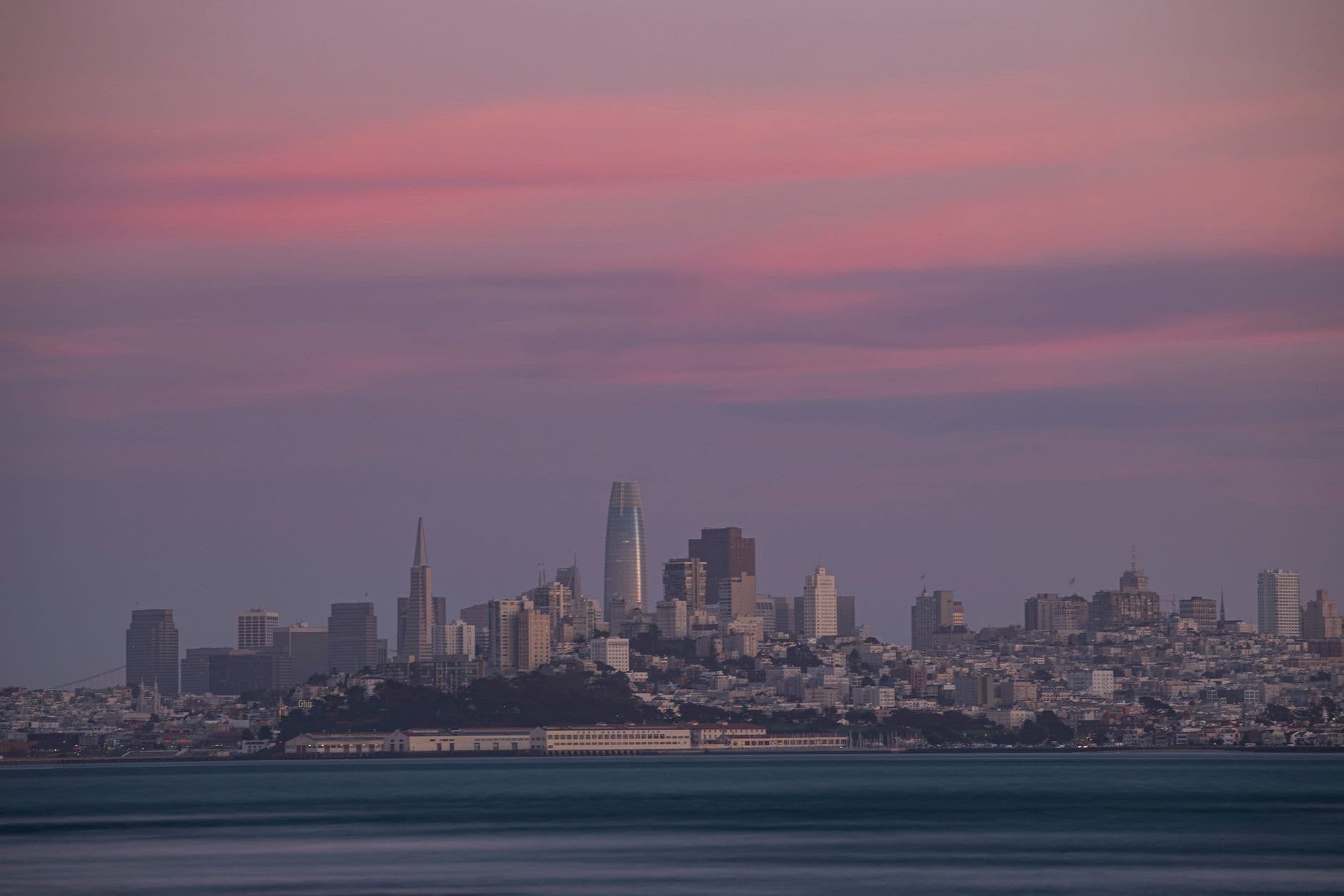 Captivating view of San Francisco skyline at twilight with vibrant pink sky.