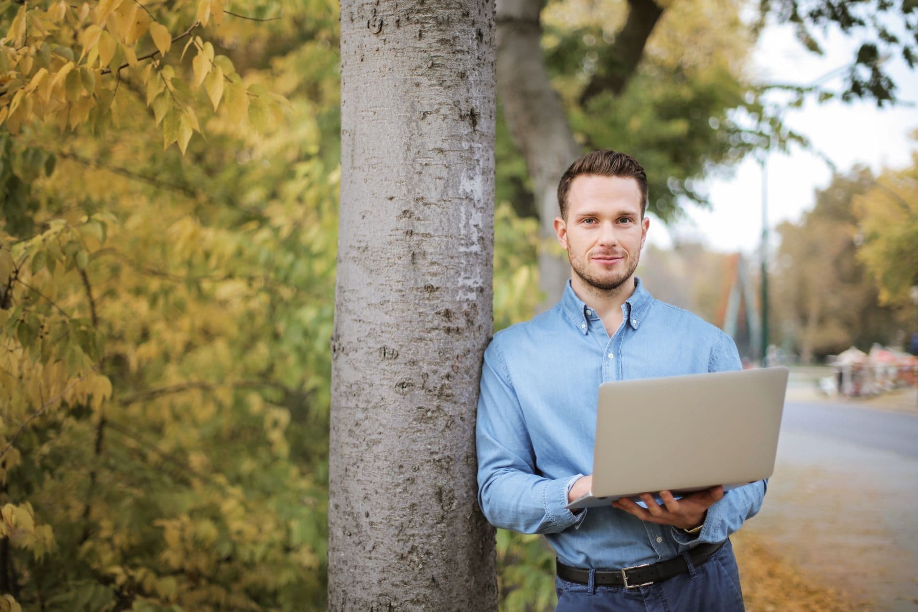 Man using laptop outdoors in a park setting, embracing digital nomad lifestyle.