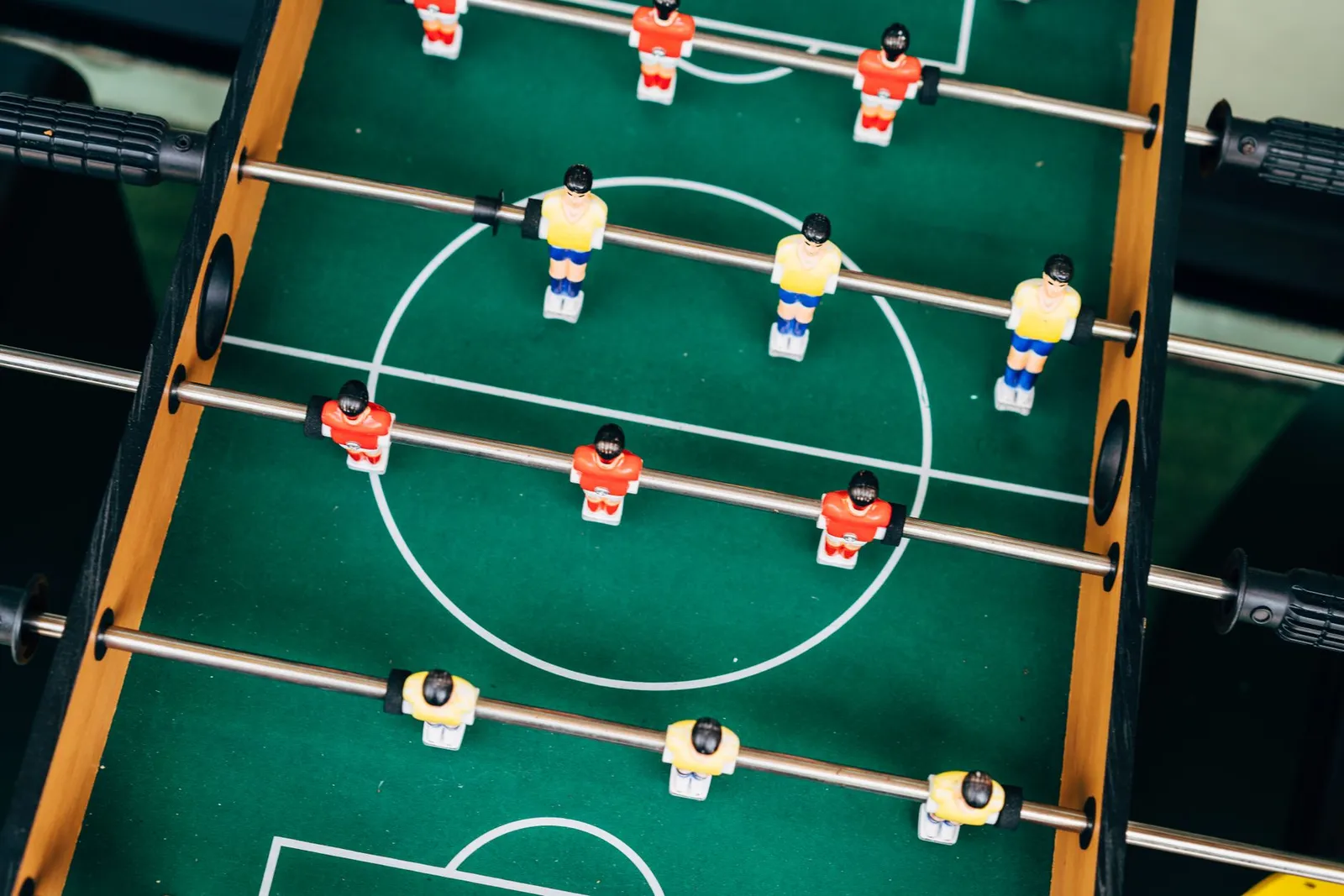 Top view of a foosball table with vibrant teams in play. Perfect for illustrating fun and competition.