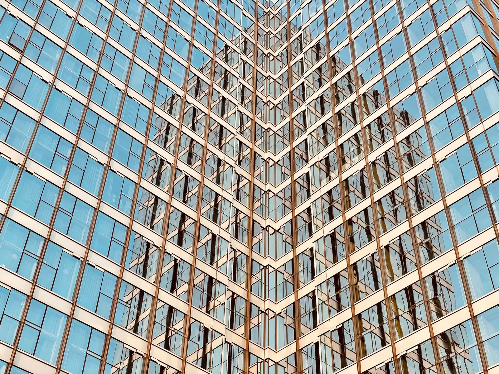 Low angle view of a reflective glass skyscraper showcasing modern architecture.