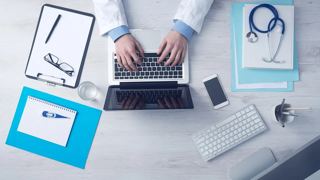 Health tech startup ideas for clinics: a doctor typing notes on a laptop