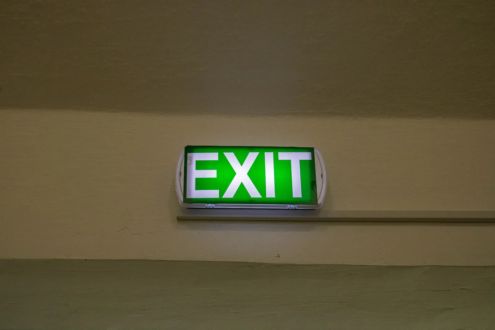 Bright green exit sign mounted on a hallway wall, offering clear direction for emergency evacuation.