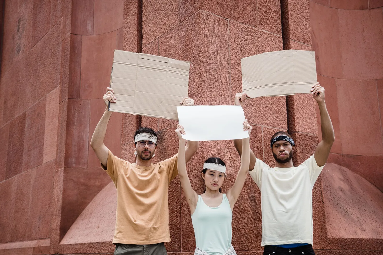 Young adults holding blank protest signs outdoors, ready for demonstration.