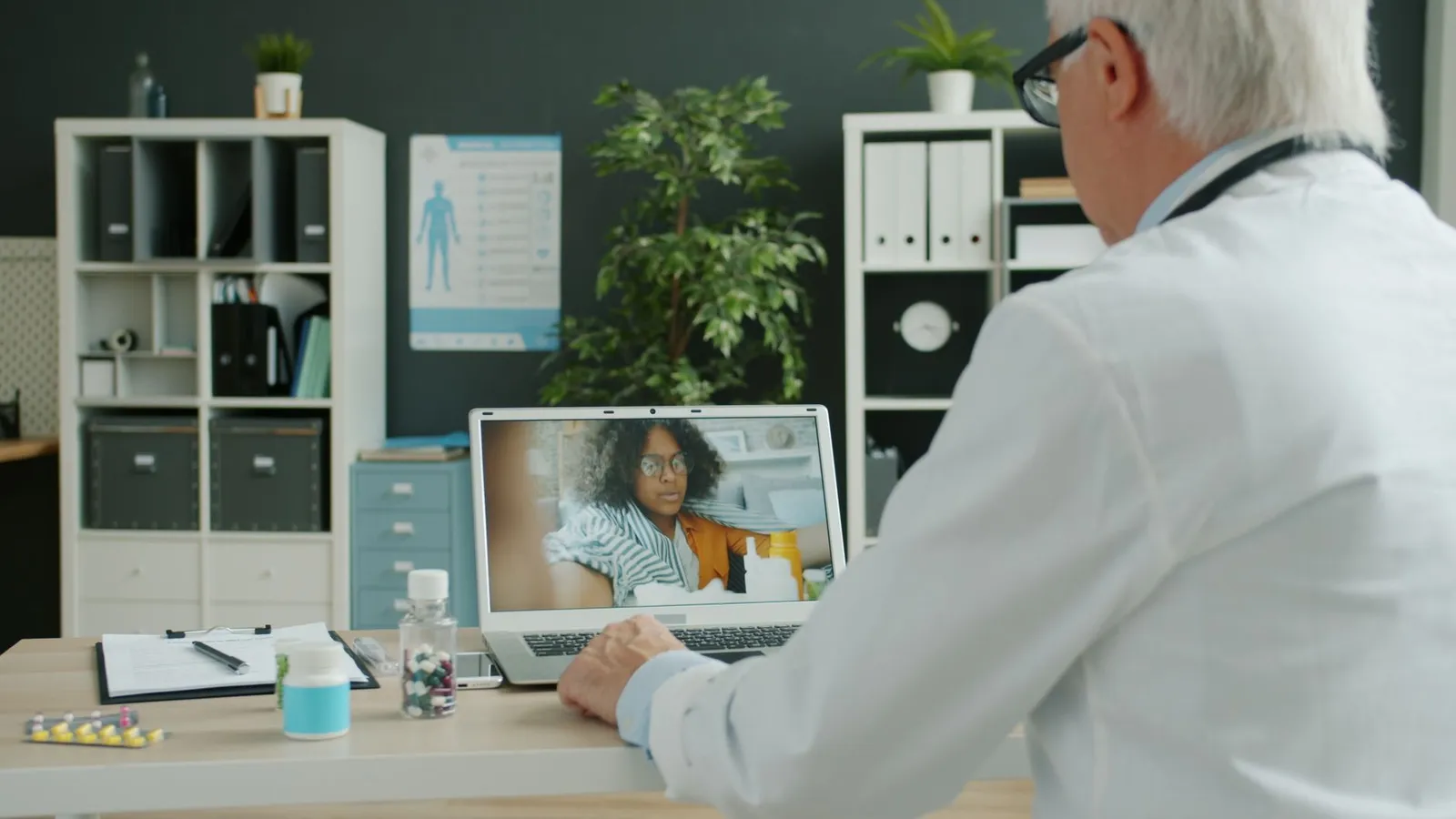 Healthcare software development trends in practice: a physician typing notes on a laptop beside a patient
