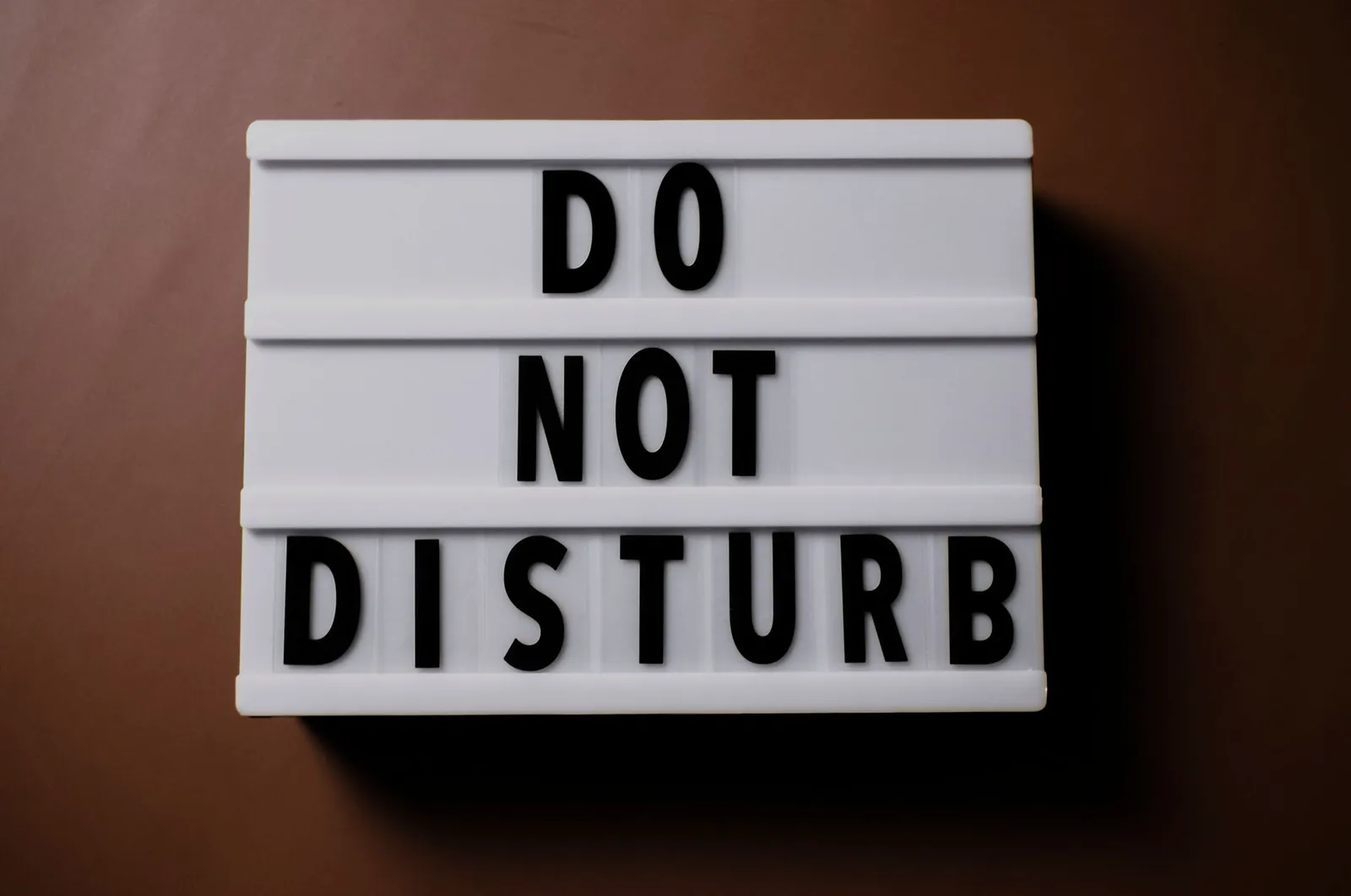 Close-up of a 'Do Not Disturb' sign on a brown surface, perfect for themes of privacy and calmness.