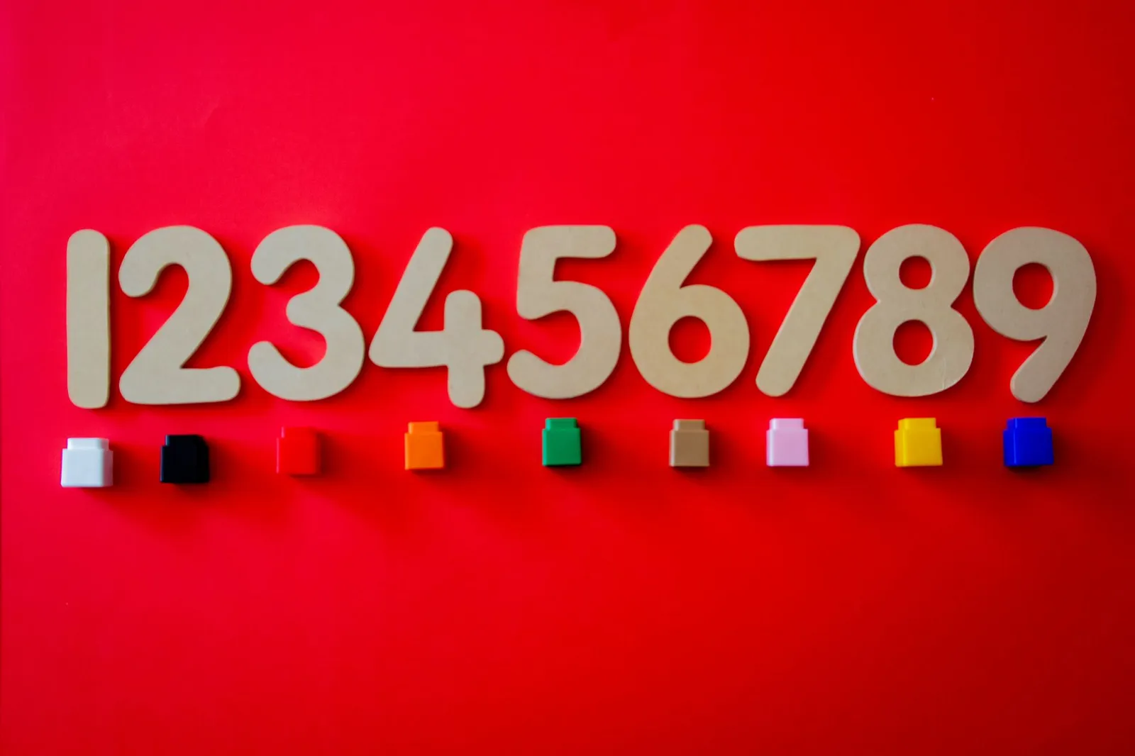 Wooden numbers with colorful cubes on a vibrant red background.