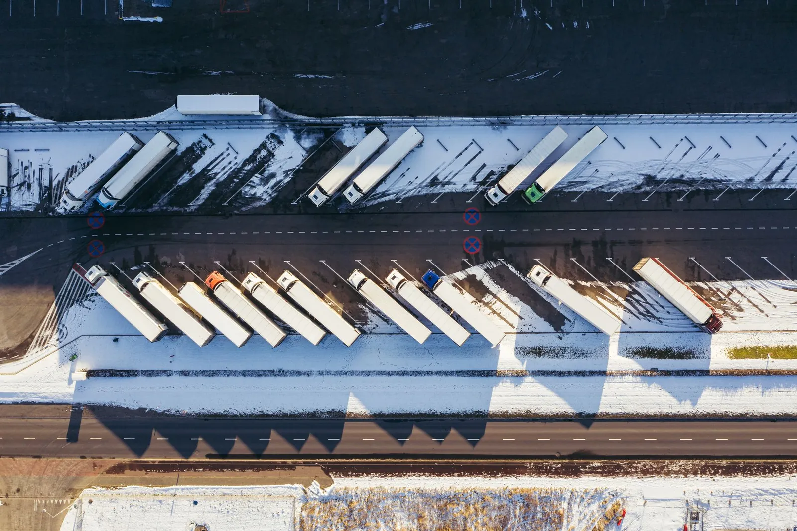 Drone shot of parked trucks next to a lush green cropland in Poznań, Poland.