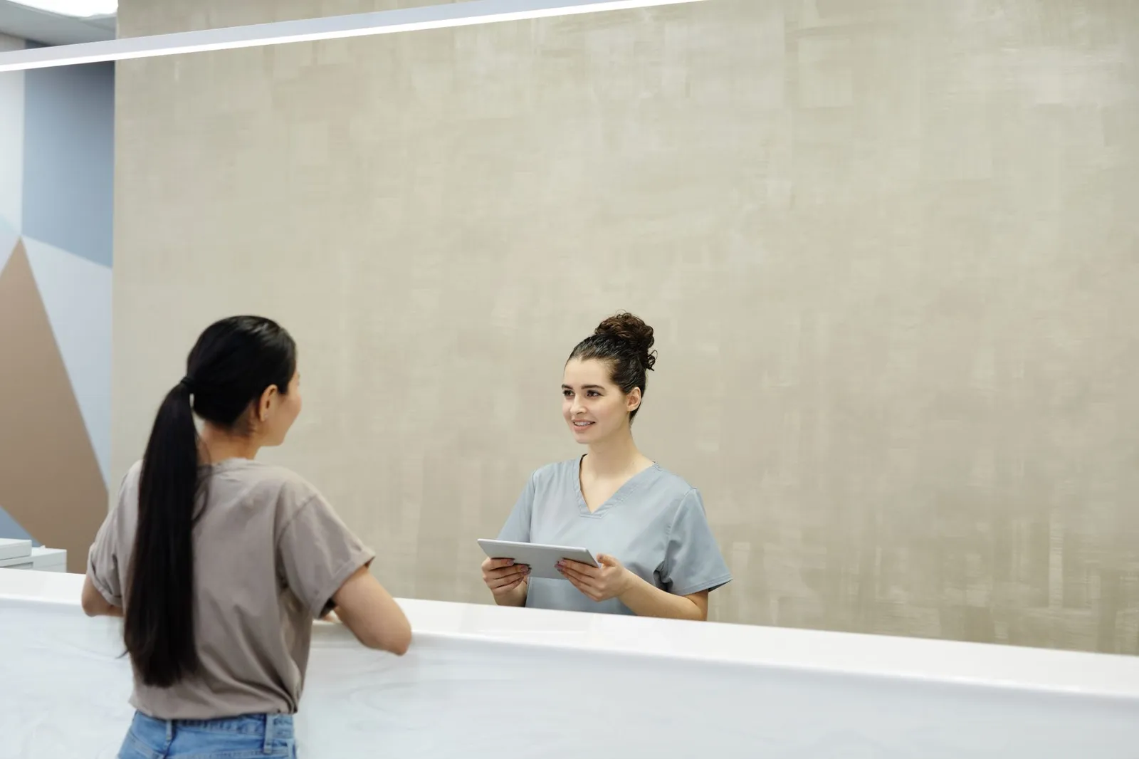 Patient engagement strategies at check-in: a receptionist helping a patient register on a tablet