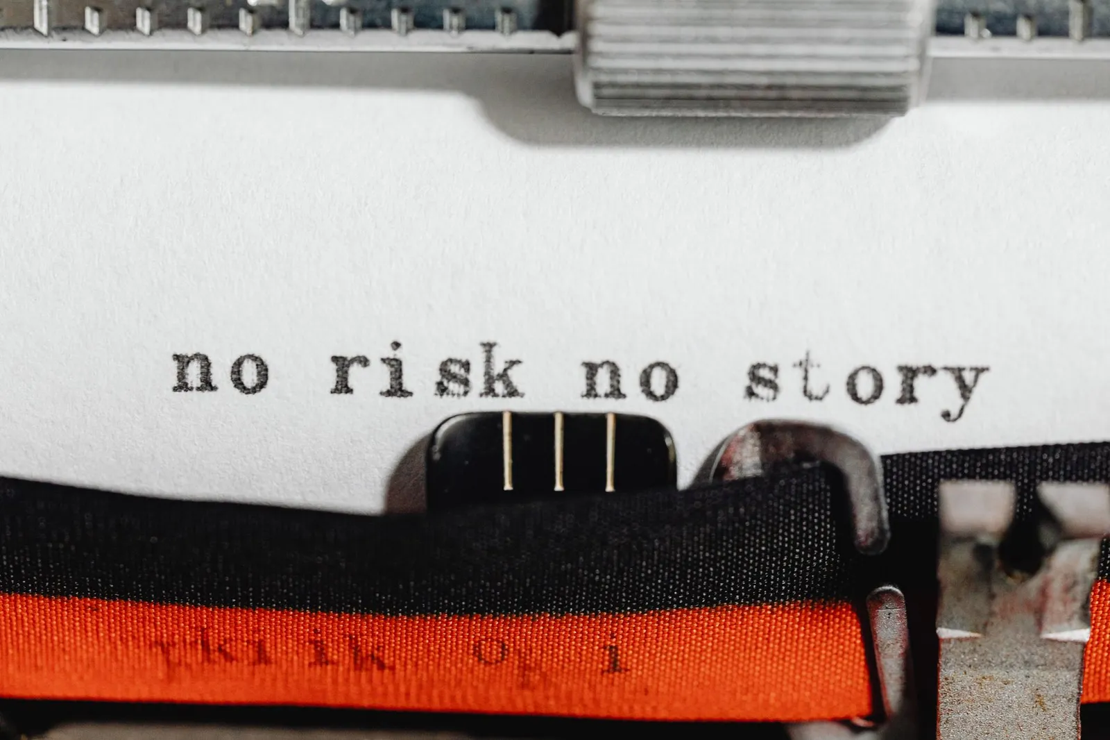 Close-up of a vintage typewriter typing 'no risk no story' on paper.