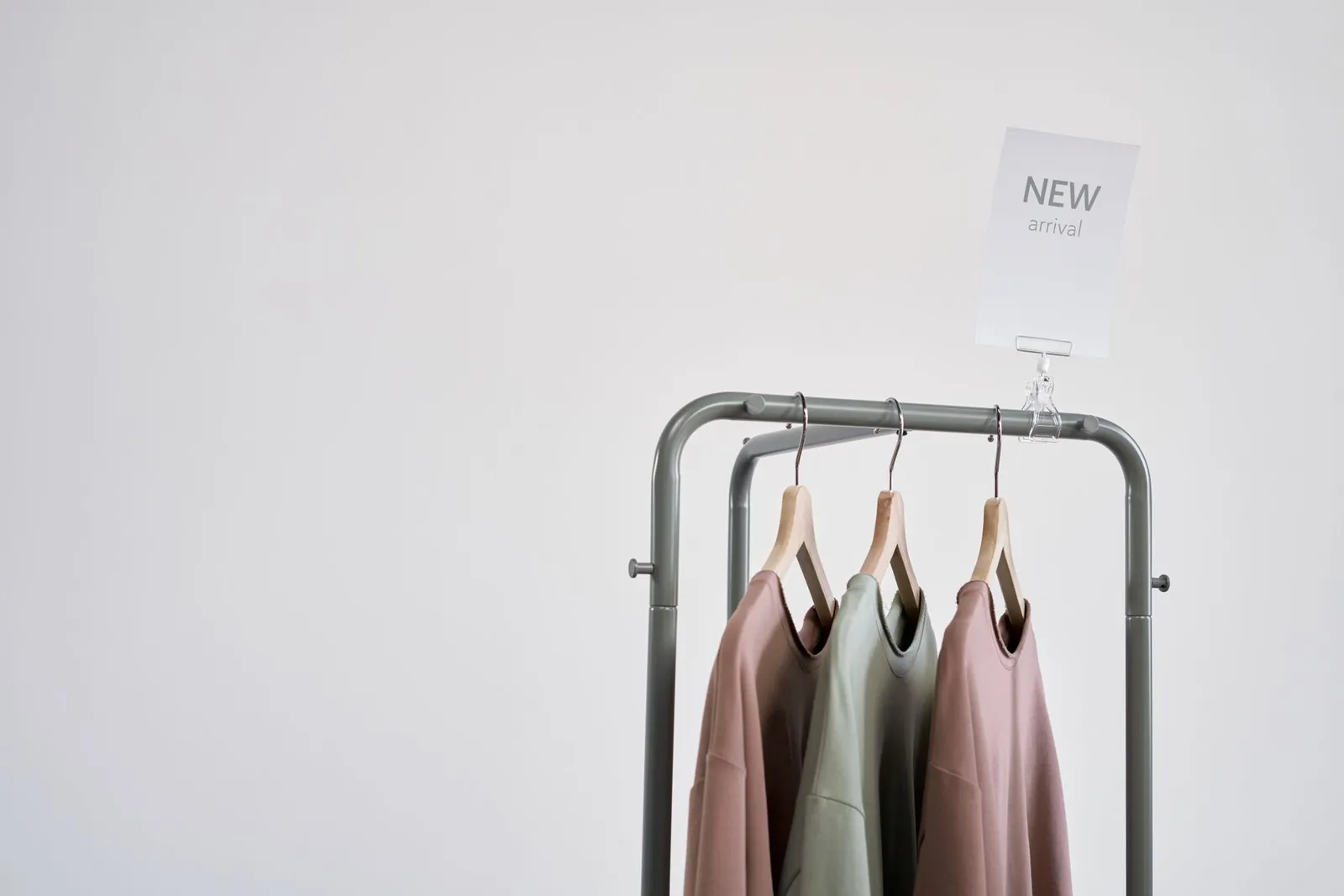 Stylish clothing on a rack with 'New Arrival' sign against a white wall.