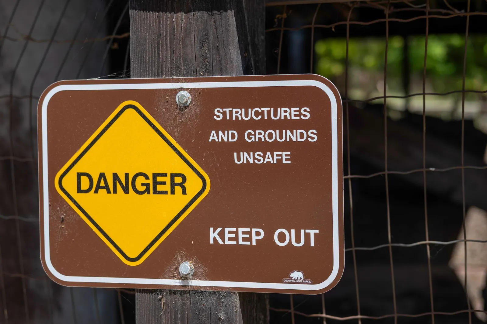 Danger sign warning about unsafe structures and grounds with keep out notice.