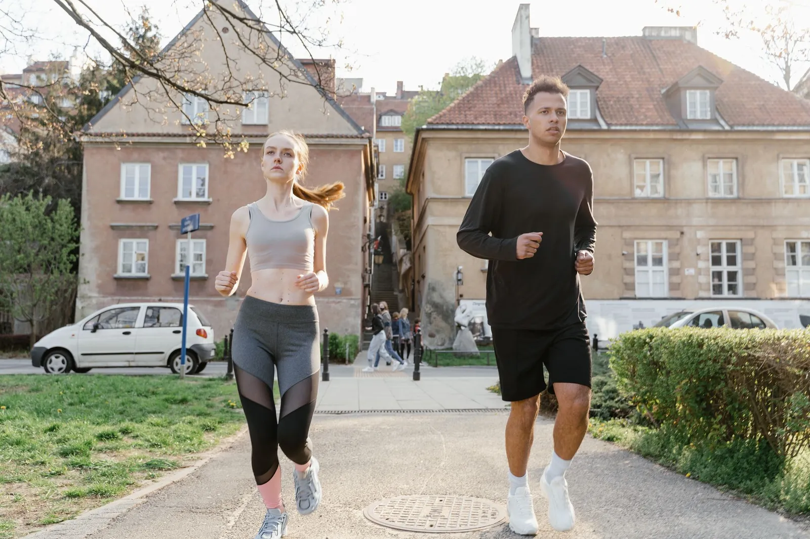 Two young adults jogging on a city path, showcasing an active lifestyle in an urban environment.