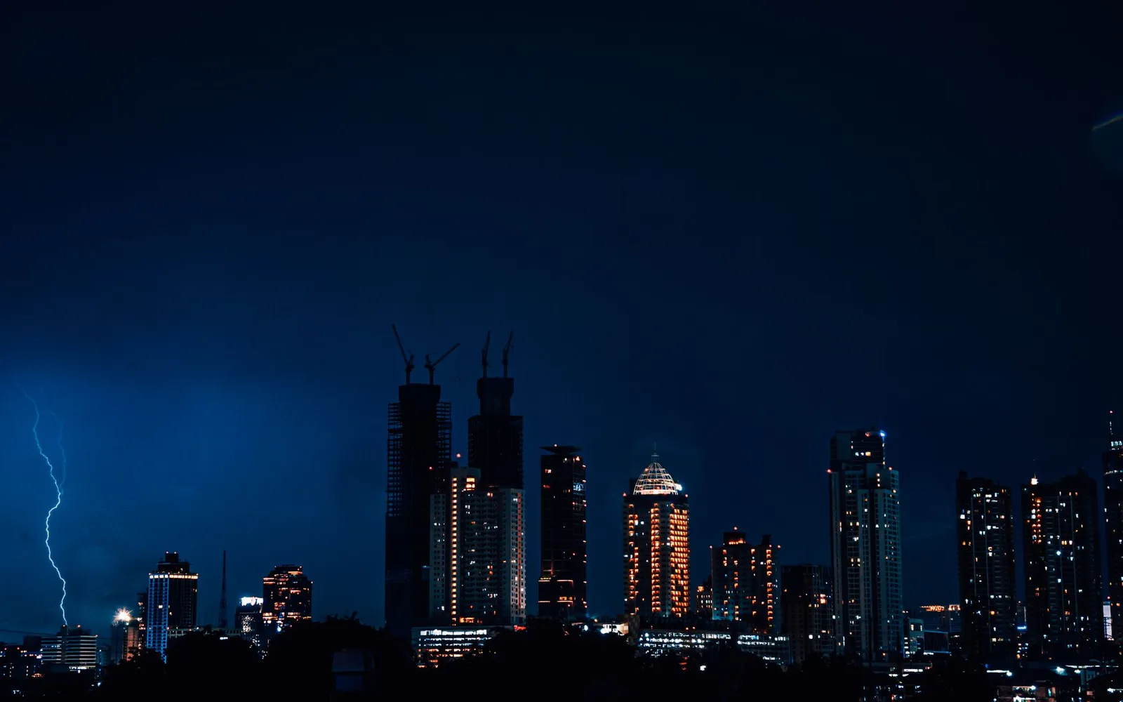 Dramatic night skyline of Jakarta with striking lightning in the sky.